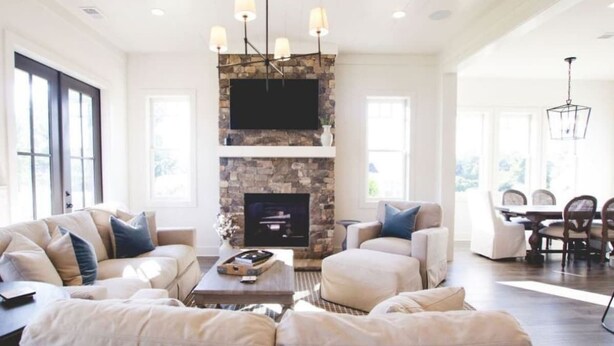 A spacious living room with a stone fireplace, a flat-screen TV, and a dining area with a table and chairs. - Luxury Farmhouse Cottage on Winery (Dahlonega)