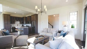 A spacious living area with a sofa set, a coffee table, and a dining area with a kitchen in the background. - Luxury Farmhouse Cottage on Winery (Dahlonega)