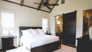 A bedroom with a large bed, a dresser, a ceiling fan, and a wardrobe. - Luxury Farmhouse Cottage on Winery (Dahlonega)