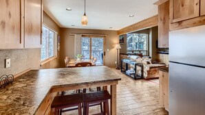 Une cuisine avec des meubles de rangement en bois, un plan de travail en granit, une table à manger avec des chaises, un canapé et un réfrigérateur.