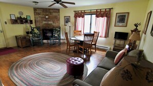 A living room with a fireplace, a dining table with chairs, a sofa, and a round rug. - Rockin Y, Romantic Getaway or Family Friendly Lodging (Gardiner)