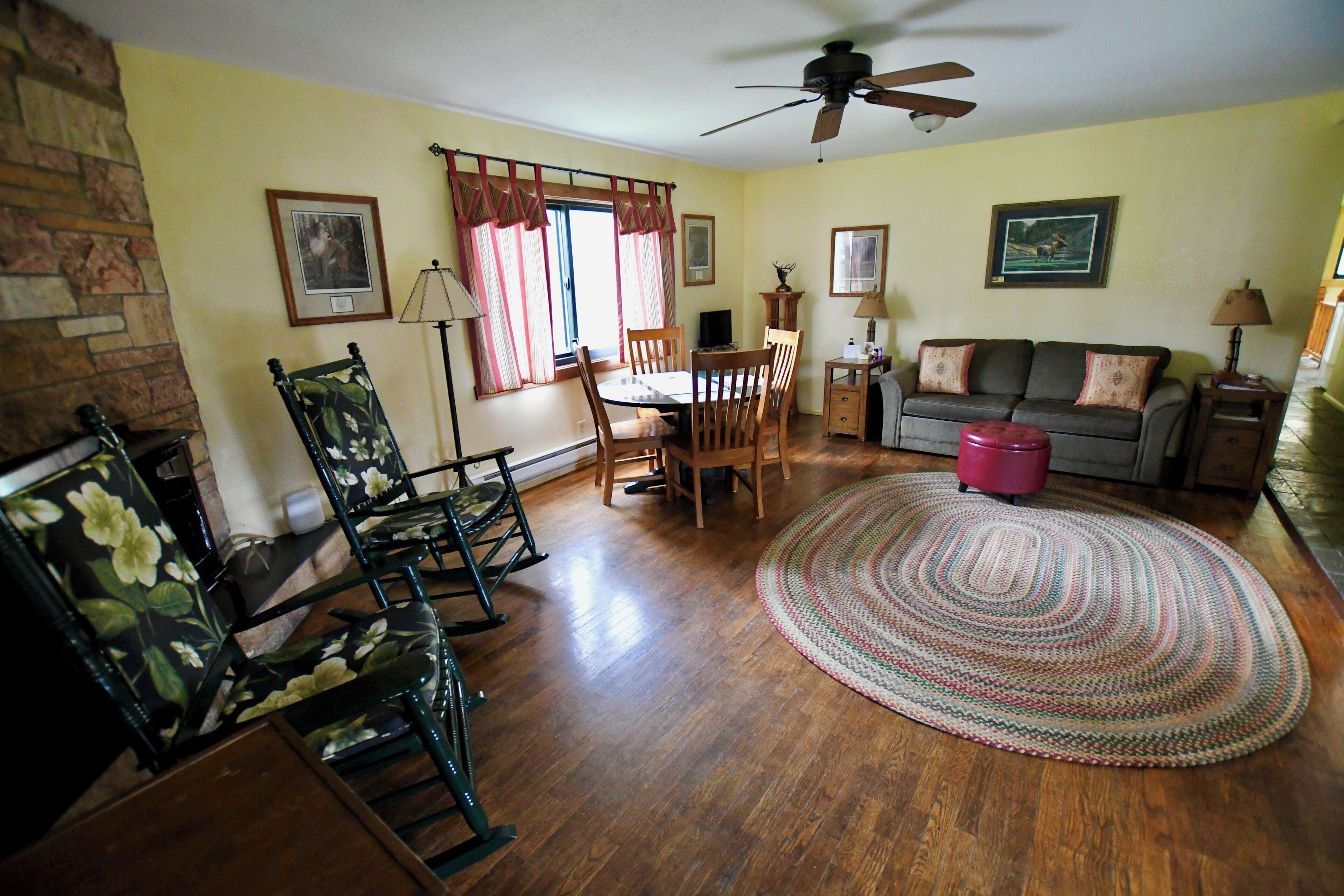 A living room with a dining table, chairs, a sofa, a fireplace, and a ceiling fan.