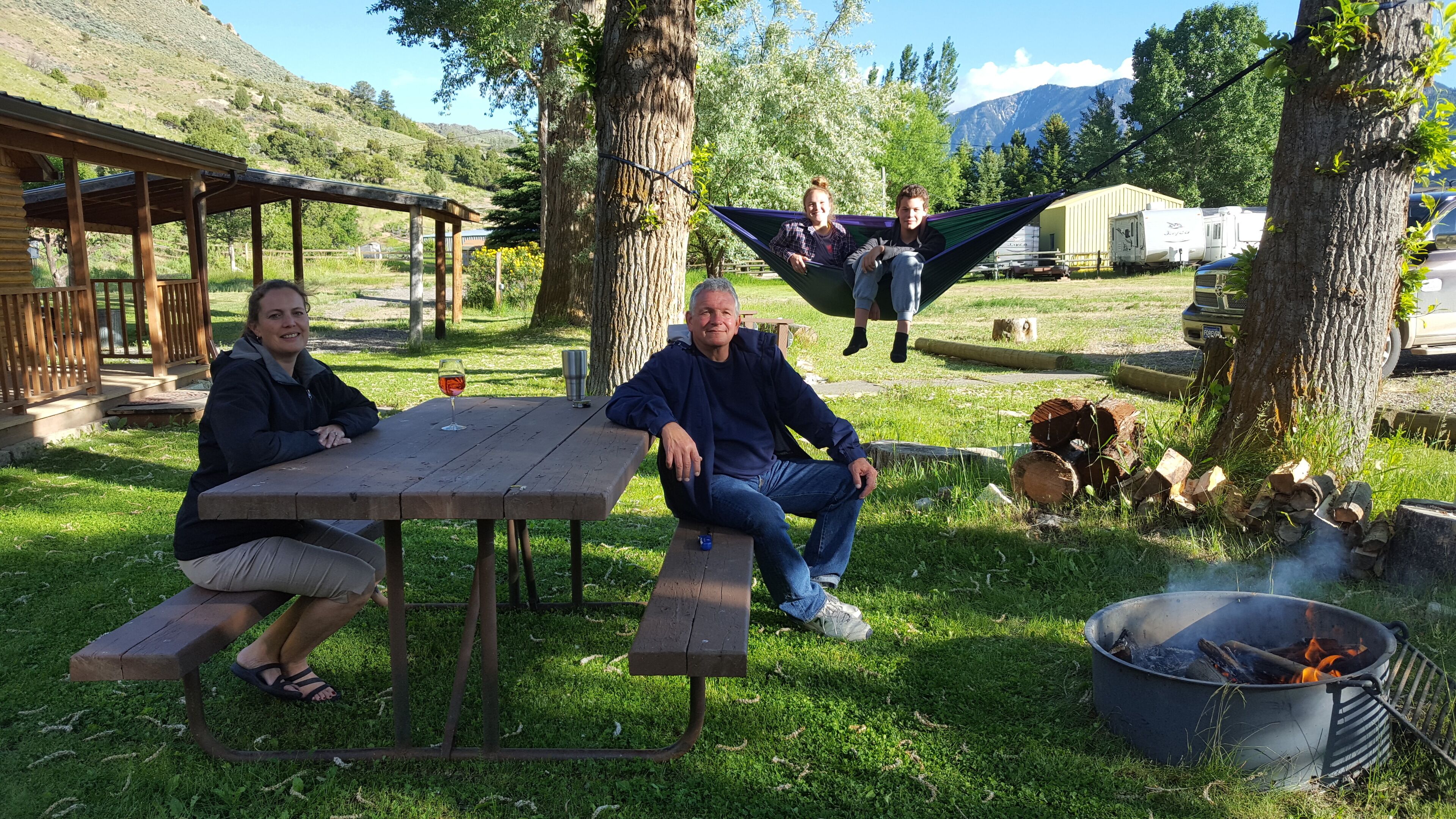 A picnic setup with a table, benches, and a fire pit.
