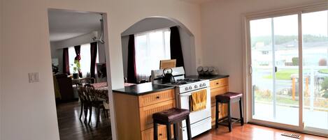 A kitchen with wooden cabinets, a stove, and two bar stools.