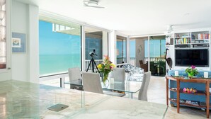 A modern living room with a glass table, chairs, and a bookshelf. - Ultimate Sanibel Beachfront! Island Beach Club, Top Floor, West-Facing, End Unit (Sanibel)