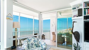 A room with a view of the ocean, a sofa, a lamp, a bookshelf, and a statue. - Ultimate Sanibel Beachfront! Island Beach Club, Top Floor, West-Facing, End Unit (Sanibel)