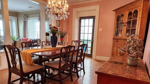 A dining area with a wooden table and chairs, a chandelier, and a cabinet with glass doors. - Curricle The third of the houses of the stone chariot (Prince Edward)