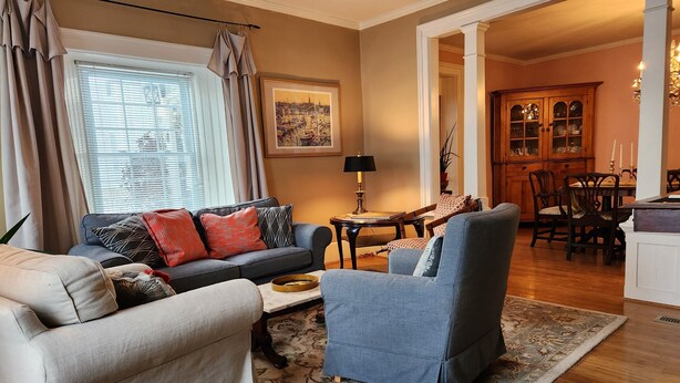 A living room with a sofa, armchair, and a coffee table. There is a dining area with a table and chairs. - Curricle The third of the houses of the stone chariot (Prince Edward)