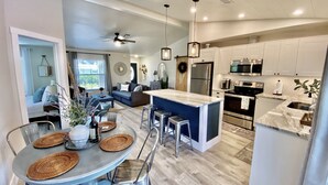 A modern kitchen with white cabinets, stainless steel appliances, and a central island. - The Casa Coco | Garden : Modern and relaxing home  with heated pool  (Venice)