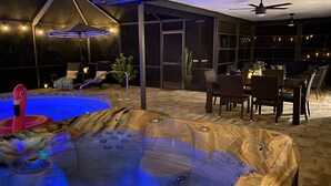 A hot tub with a wooden exterior and a pool with a pink flamingo float. - The Casa Coco | Garden : Modern and relaxing home  with heated pool  (Venice)