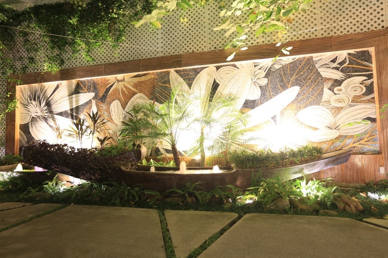 A decorative wall with a relief of tropical plants and a water feature.