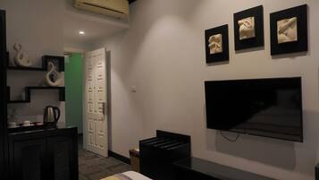 A modern hotel room with a flat-screen TV, a bed, a coffee maker, and a small trash bin.