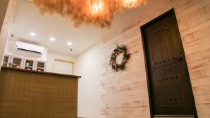 Un área de recepción con un mostrador de madera, una puerta de madera oscura y un adorno colgante en la pared.