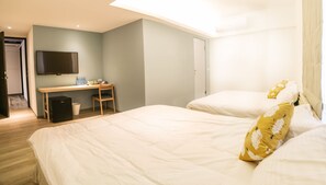 A hotel room with two beds, a desk, a chair, a television, and a trash bin.
