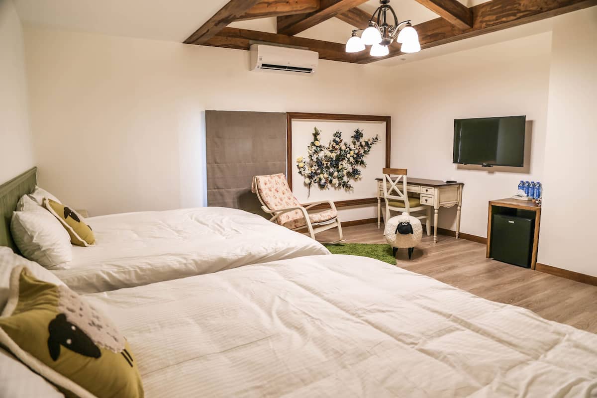 Un dormitorio con dos camas, un escritorio, una silla, un televisor y un equipo de aire acondicionado.