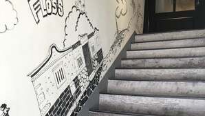 Una escalera con un mural en la pared que muestra una ilustración de un edificio y el texto "Candy Floss".