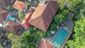 An aerial view of a residential area with multiple houses, a swimming pool, and lush greenery. - ADI JAYA COTTAGES (Ubud)