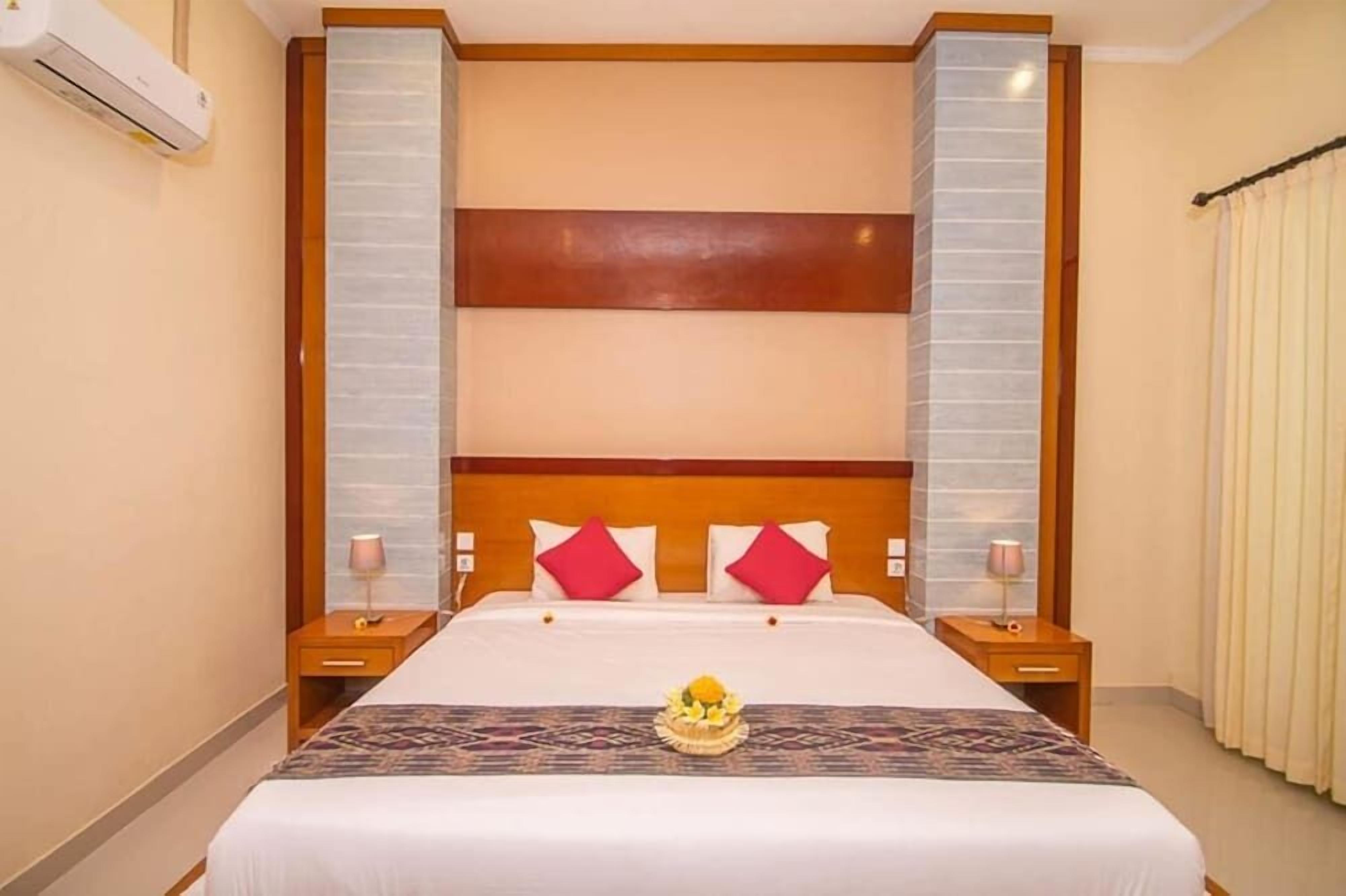 A hotel room with a large bed, wooden headboard, two bedside tables, and a decorative centerpiece on the bed.
