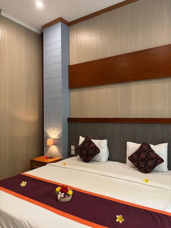 A hotel room with a bed, a nightstand, a lamp, and a floral arrangement.