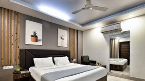 Un dormitorio moderno con una cama grande, cabecera de madera, mesitas de noche, ventilador de techo y equipo de aire acondicionado.