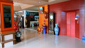 Um saguão com piso lustroso, paredes vermelhas e decoração tradicional chinesa, incluindo vasos e um relógio.