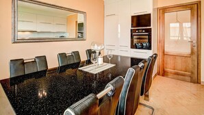 A modern dining area with a black granite table, six chairs, and a large mirror on the wall.