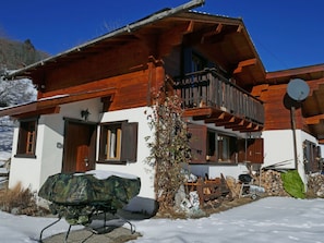 Un chalet con un balcone in legno, un'antenna parabolica e una griglia coperta.