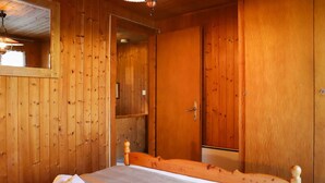 Una habitación de madera con una cama, una puerta y un espejo.