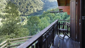 Un balcón de madera con vistas a un valle boscoso y montañas.