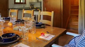 Una mesa de madera para comer dispuesta con platos, vasos y cubiertos, y una servilleta que dice 'Happy'.