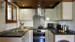 Una cocina moderna con armarios blancos, una campana extractora de acero inoxidable, un microondas y un lavabo con un bloque de cuchillos.