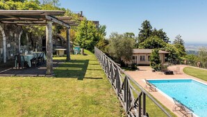 Ein Poolbereich mit Pergola, Sitzmöglichkeiten im Freien und Blick auf die Landschaft.