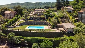 Eine Villa mit Swimmingpool, umgeben von üppiger Vegetation und Hügeln.