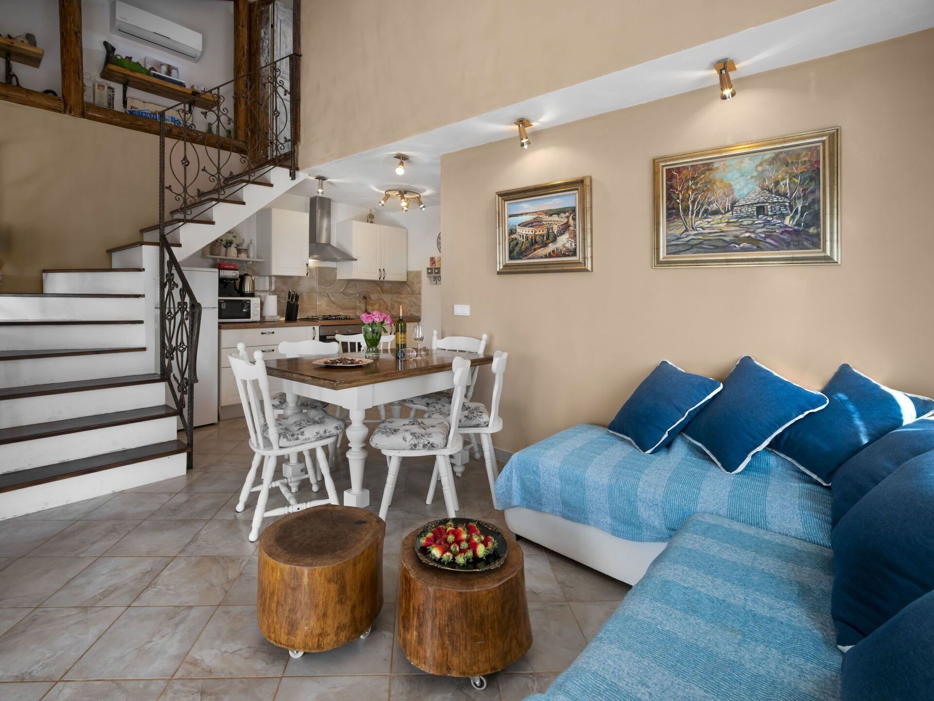 A modern living room with a staircase, dining area, and kitchen.