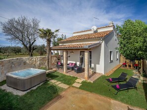 Uma casa com varanda, hidromassagem e cadeiras de descanso.