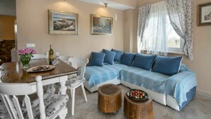 A cozy living room with a wooden dining table, white chairs, a blue sofa, and two wooden side tables. - Stunning private villa with hot tub, private pool, A/C, WIFI, TV, terrace and pets allowed (Loborika)