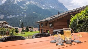 Ein Holztisch mit einer Kanne und Gläsern, vor einer Bergkulisse.