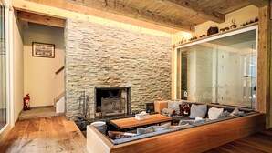 Ein gemütliches Wohnzimmer mit Kamin aus Stein, Holzdielen und einer eingebauten Couch.
