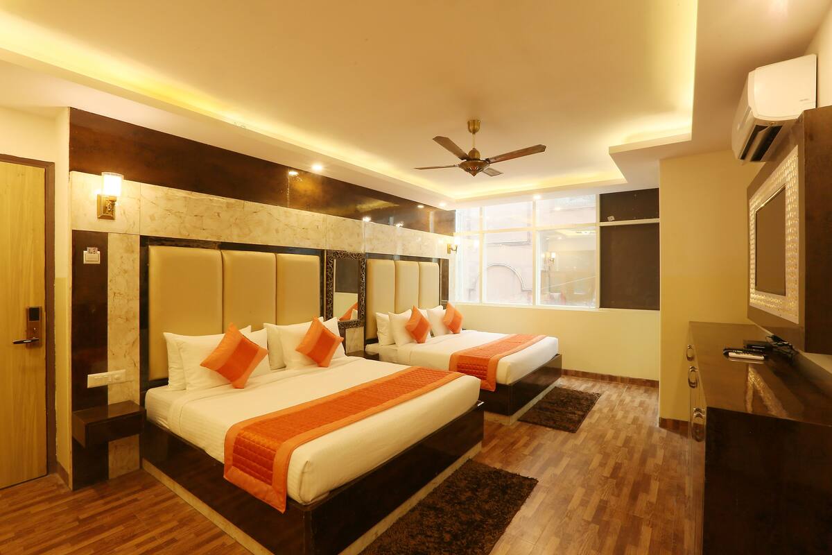 A hotel room with two beds, a ceiling fan, and a large window.