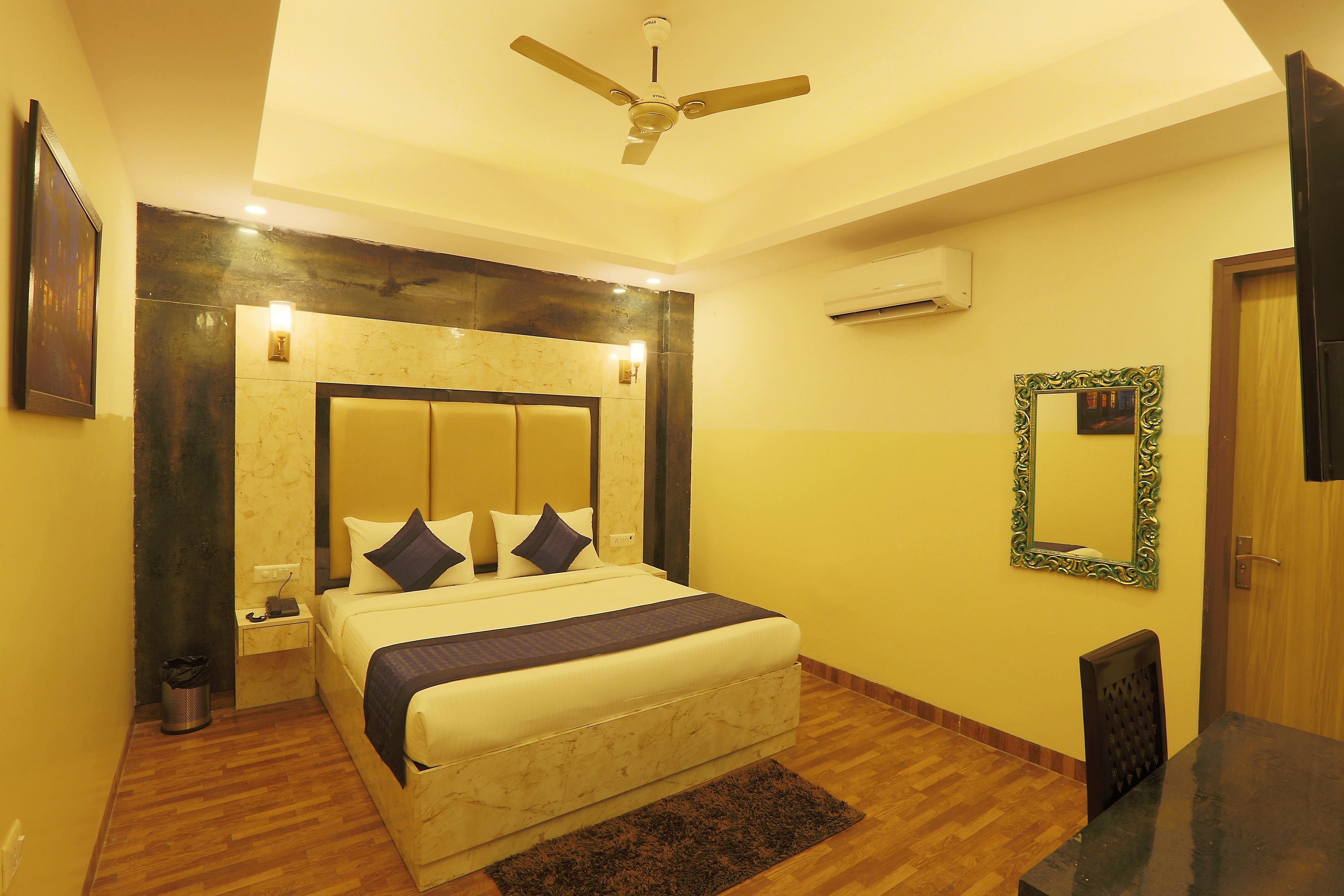 A hotel room with a bed, bedside table, nightstand, and a ceiling fan.