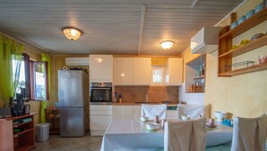 A compact kitchen with a refrigerator, oven, and sink. There is a dining table with chairs and a blue rug. - Lovely apartment for 4 people with WIFI, A/C, TV, terrace and pets allowed (Senj)