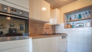 A modern kitchen with white cabinetry, a stainless steel oven, a wooden countertop, and a built-in shelf with kitchen items. - Lovely apartment for 4 people with WIFI, A/C, TV, terrace and pets allowed (Senj)