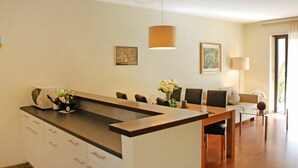 Une cuisine moderne dotée d’un îlot central, de meubles blancs et d’un coin repas avec une table et des chaises.
