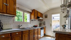 Cucina con mobili in legno, lavandino in acciaio inossidabile e finestra che lascia entrare luce naturale.