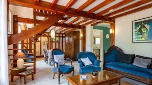 Un soggiorno spazioso con soffitto in legno, un divano blu e poltrone abbinate.