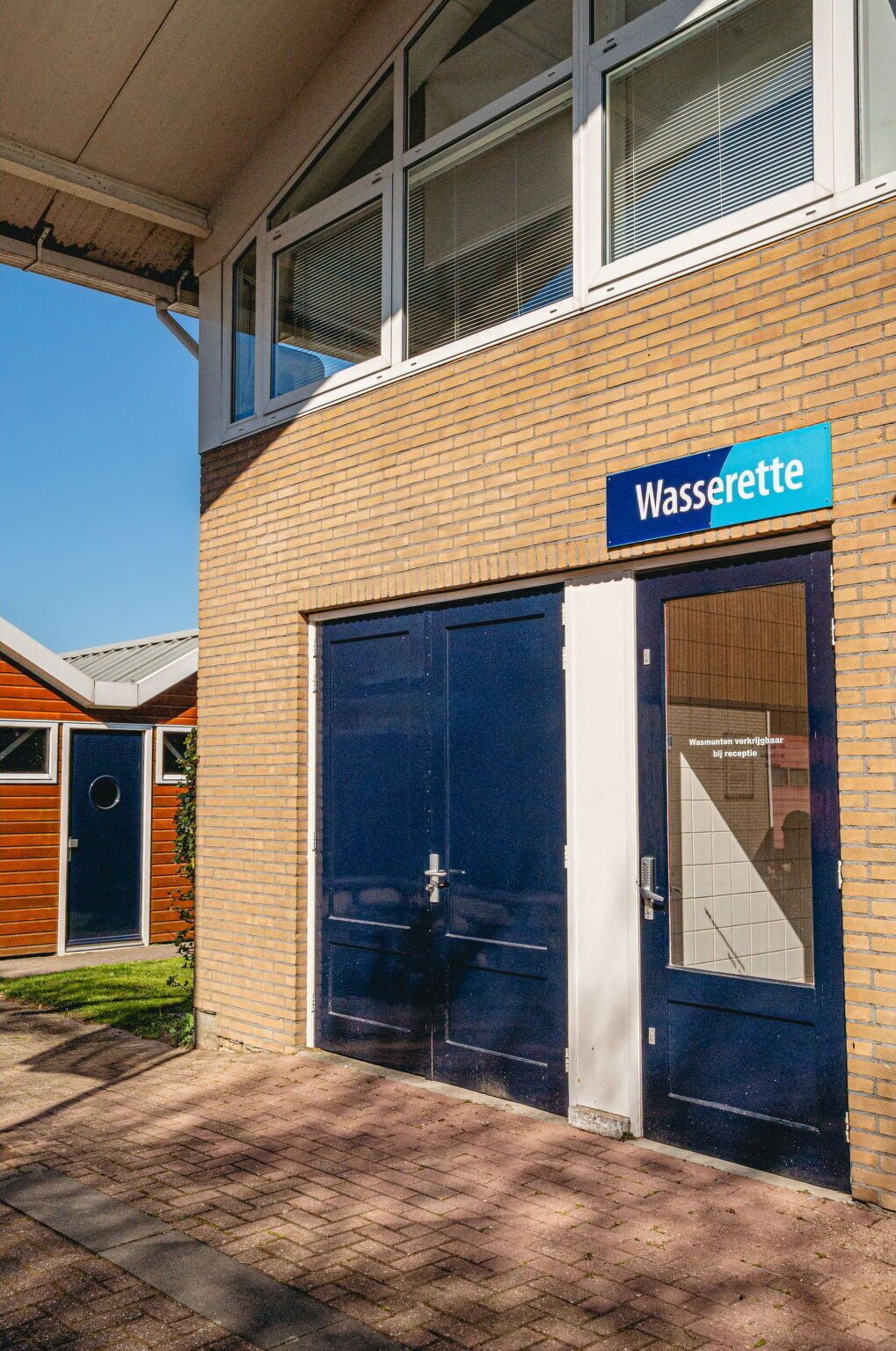 A building with a sign reading "Wasserette" and a large garage door.