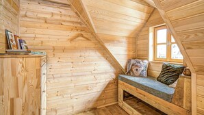 A cozy attic bedroom with wooden walls, a sloped ceiling, a window, and a built-in bench with pillows. - Wonderful private villa for 4 people with A/C, WIFI, TV and pets allowed (Vrelo Korenicko)