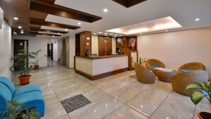 A hotel lobby with a reception desk, seating area, and potted plants. - Hotel Pride (Kharar)