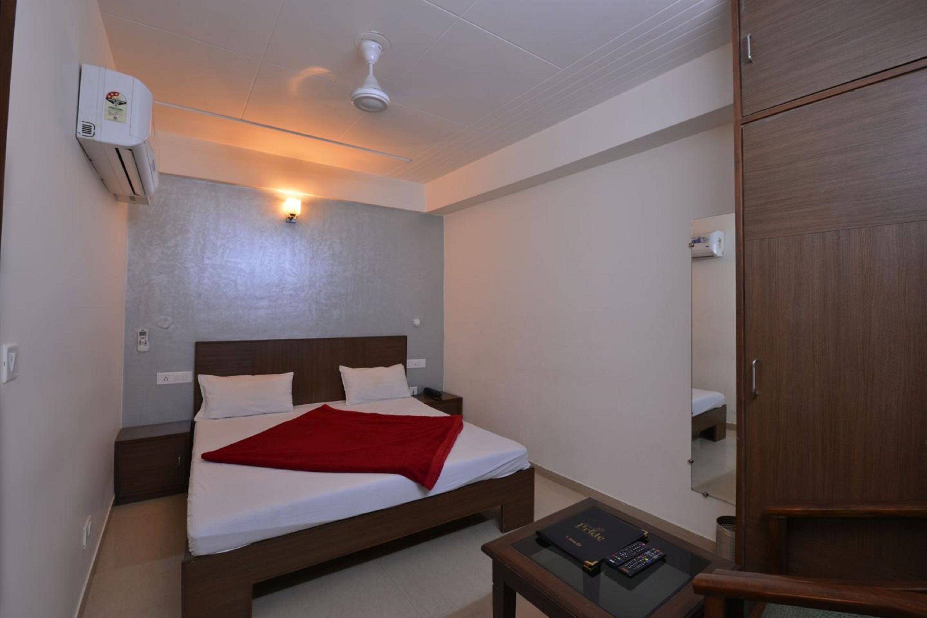 A hotel room with a bed, bedside table, and a wardrobe.