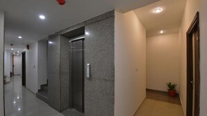 A modern hallway with a granite wall, a door, and a small potted plant. - Hotel Pride (Kharar)